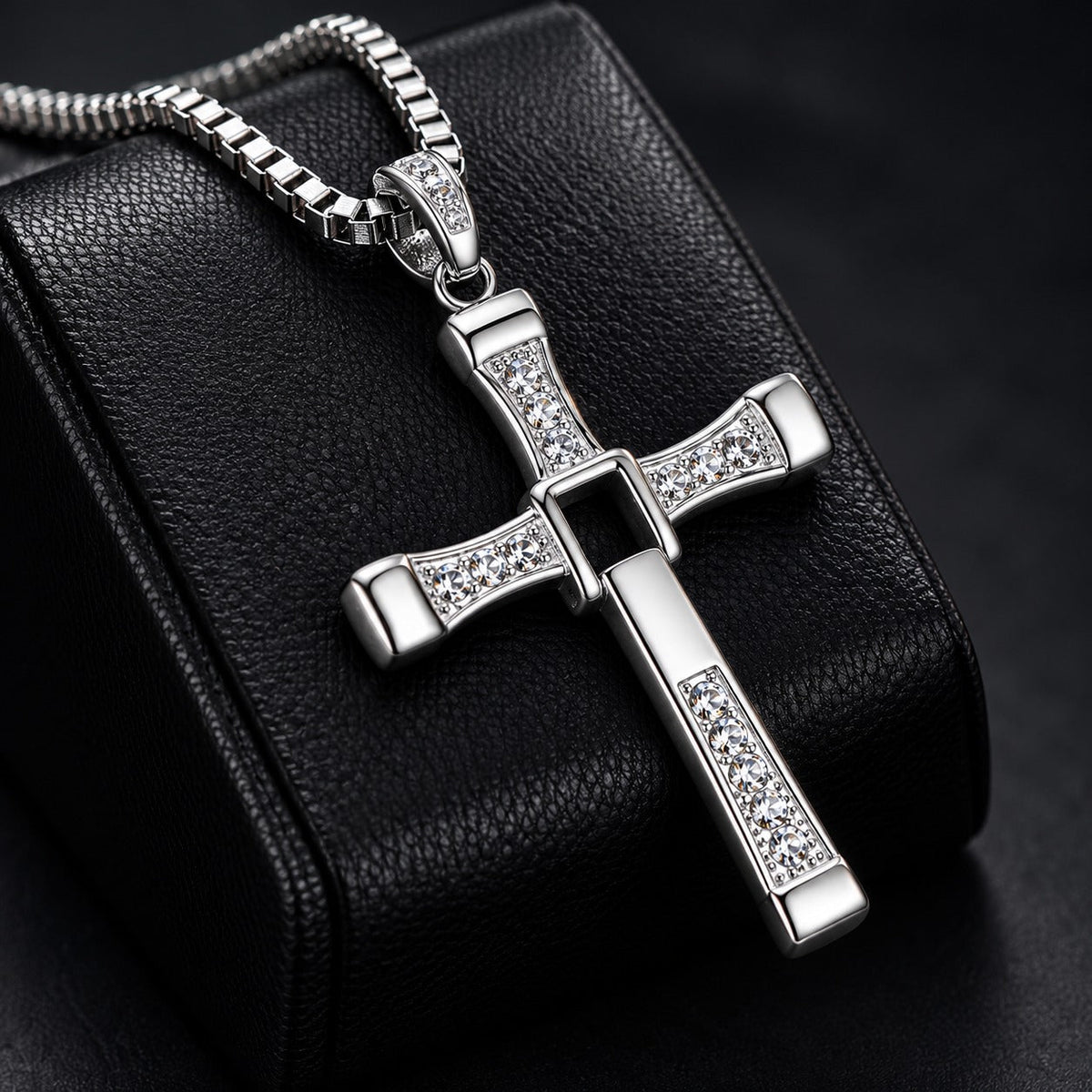 Fidelink cross necklace resting on black leather
